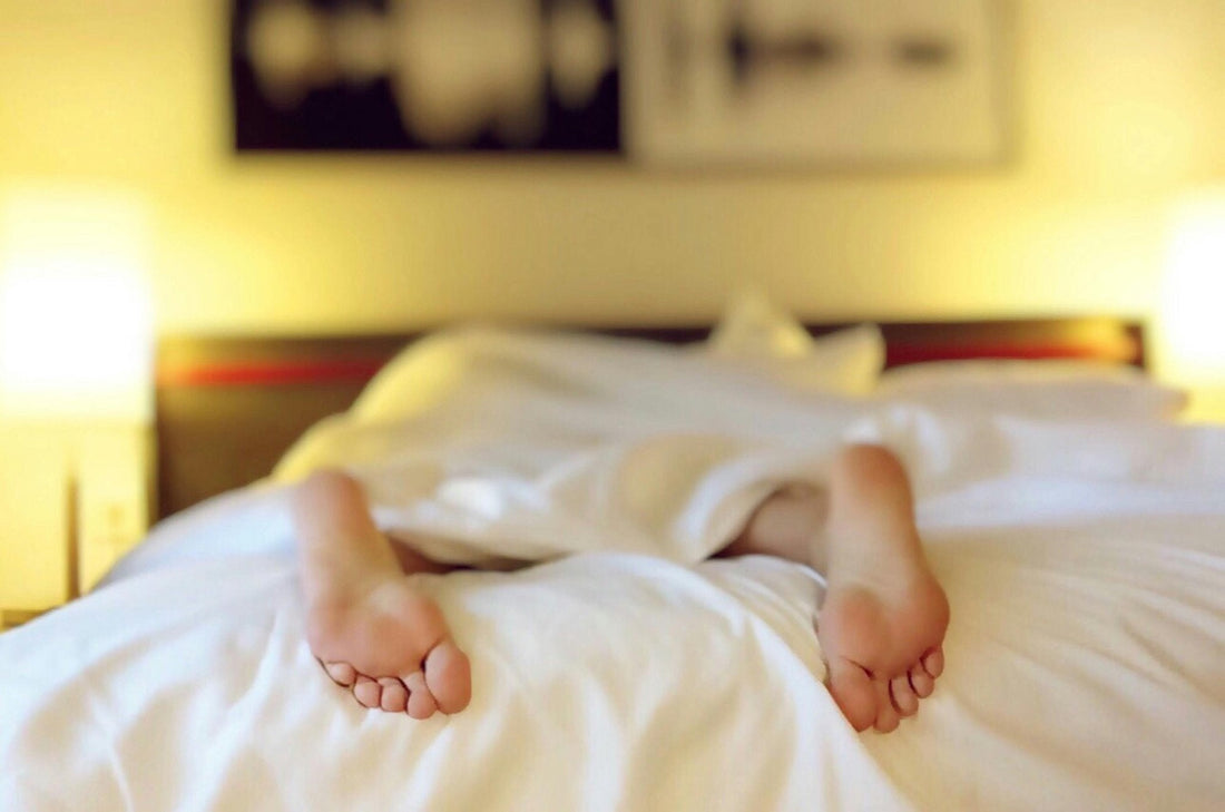 person lying in bed with feet sticking out of blanket